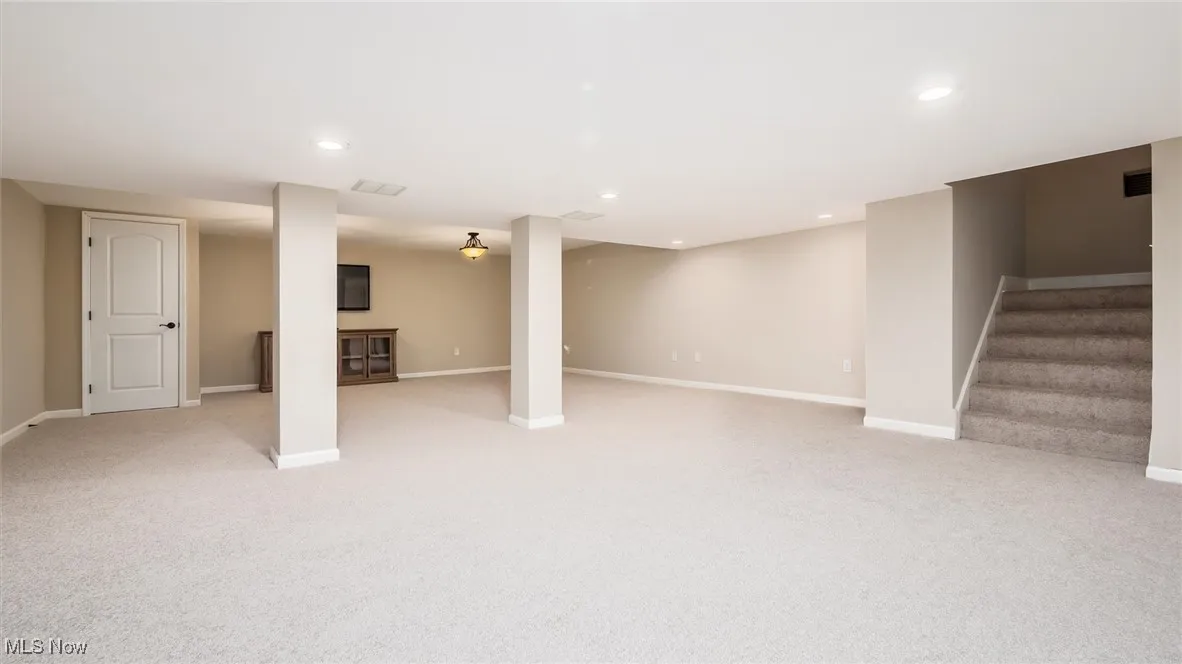 Finished basement featuring light carpet, baseboards, stairs, and recessed lighting