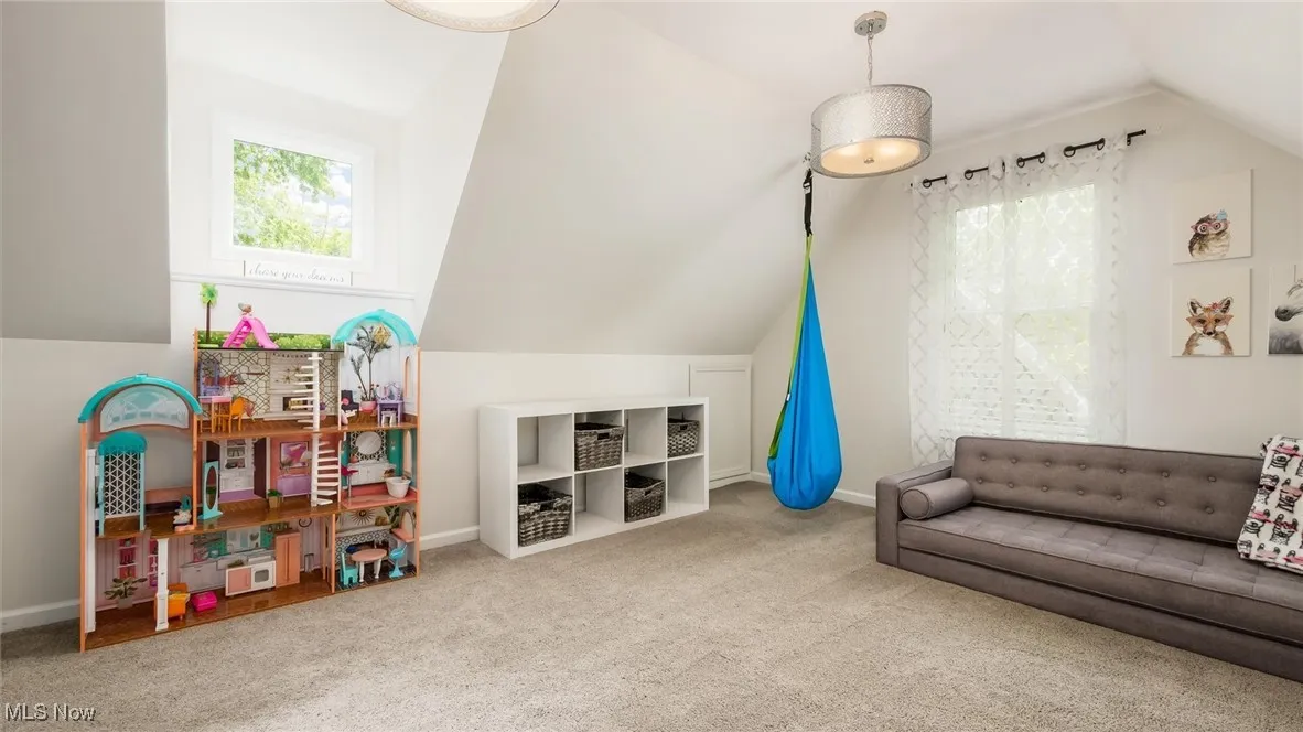 Carpeted living area featuring vaulted ceiling and baseboards
