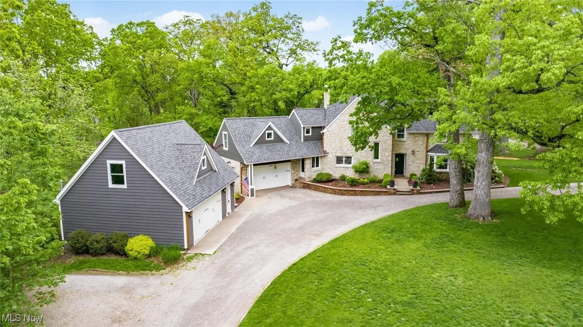 View of front of house featuring asphalt driveway, a front lawn, a chimney, roof with shingles, and a garage