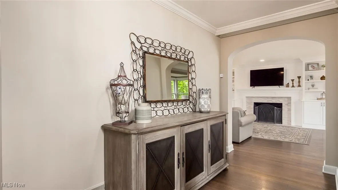 Hall featuring ornamental molding, dark wood-type flooring, arched walkways, and baseboards