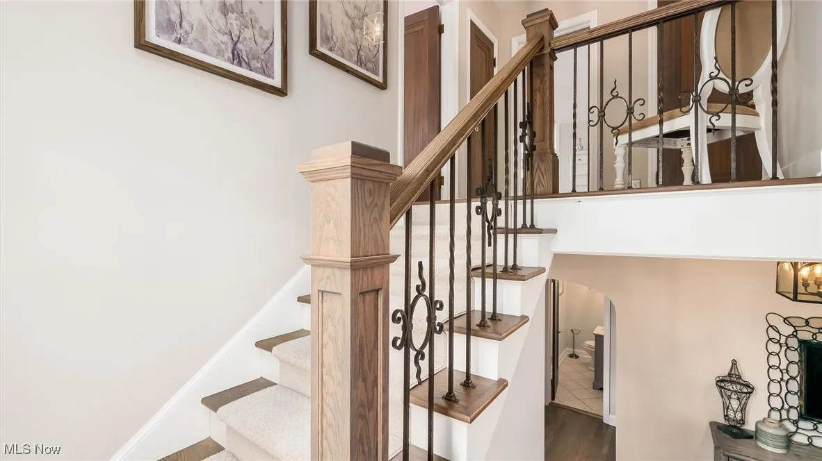 Staircase featuring arched walkways and wood finished floors