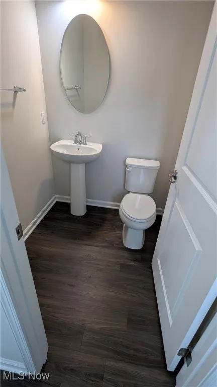 Bathroom with baseboards, toilet, and wood finished floors