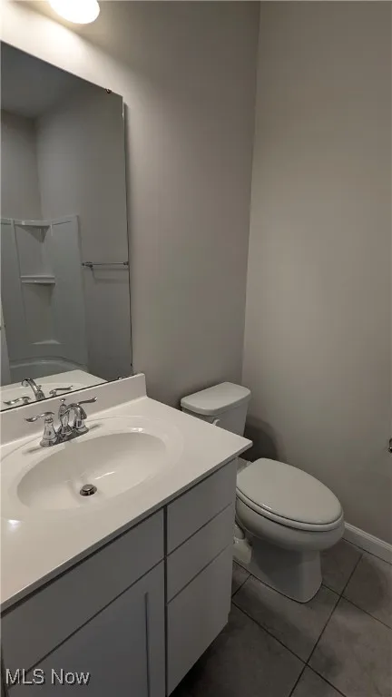 Bathroom with tile patterned flooring, toilet, vanity, and a shower