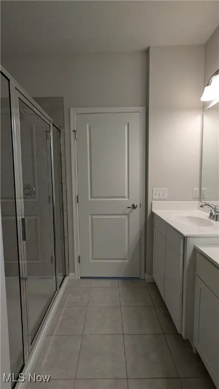 Full bathroom with a stall shower, vanity, tile patterned flooring, and a textured ceiling