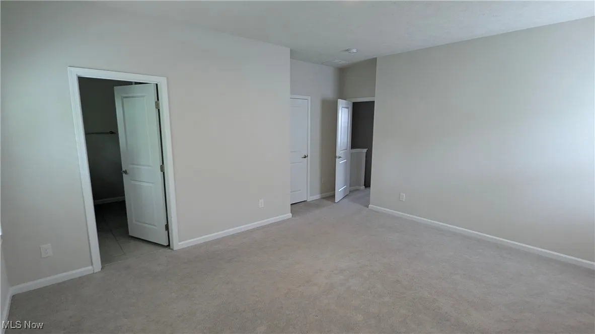 Unfurnished bedroom with light colored carpet and baseboards