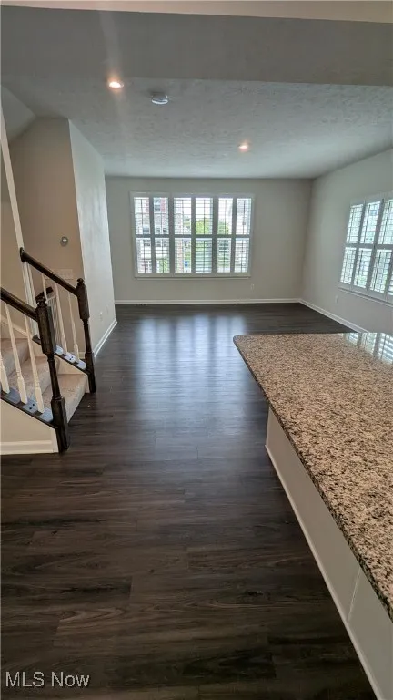 Spare room featuring plenty of natural light, baseboards, dark wood finished floors, recessed lighting, and a textured ceiling