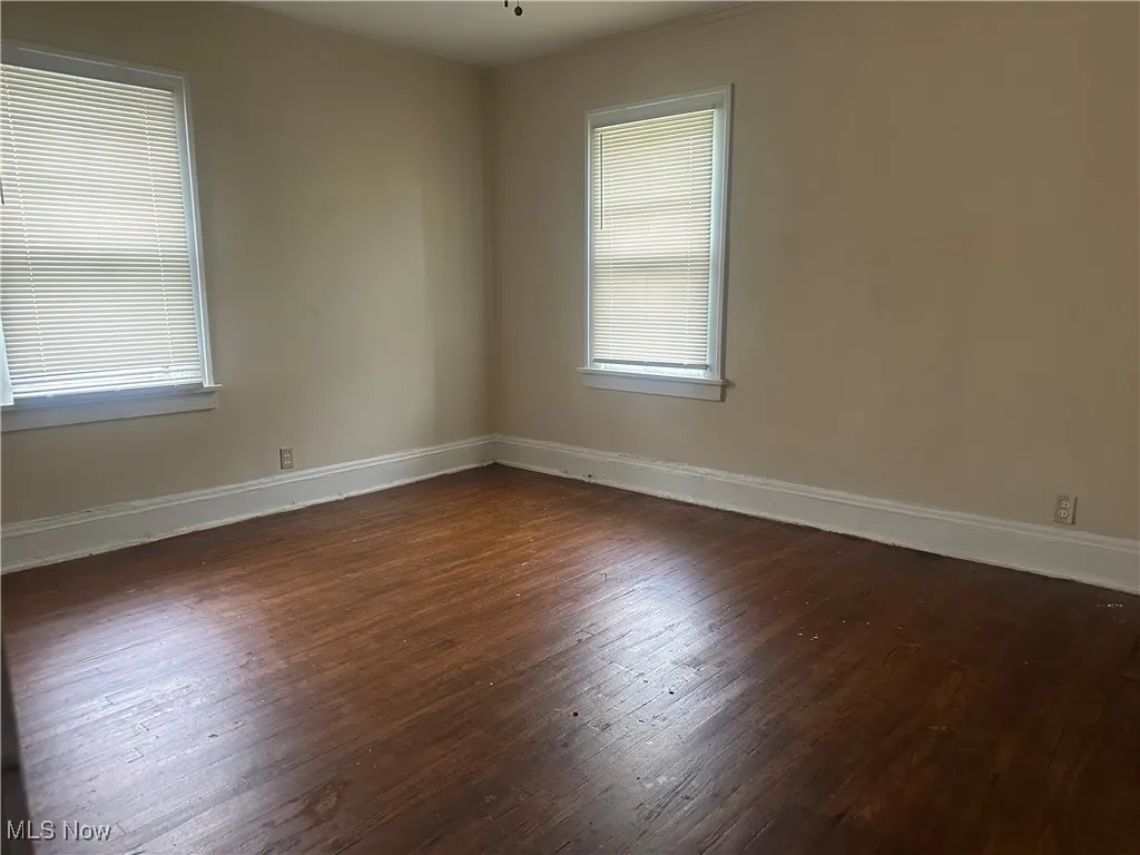 Spare room featuring wood finished floors, baseboards, and healthy amount of natural light