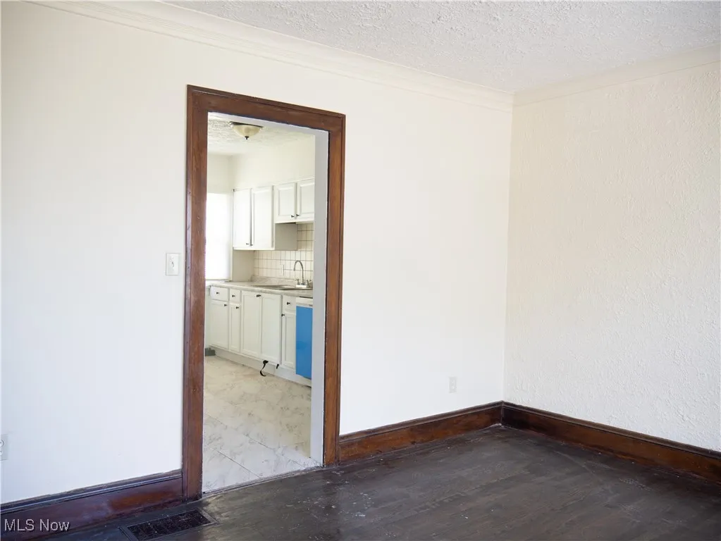 Spare room featuring wood finished floors, a textured ceiling, a sink, and baseboards