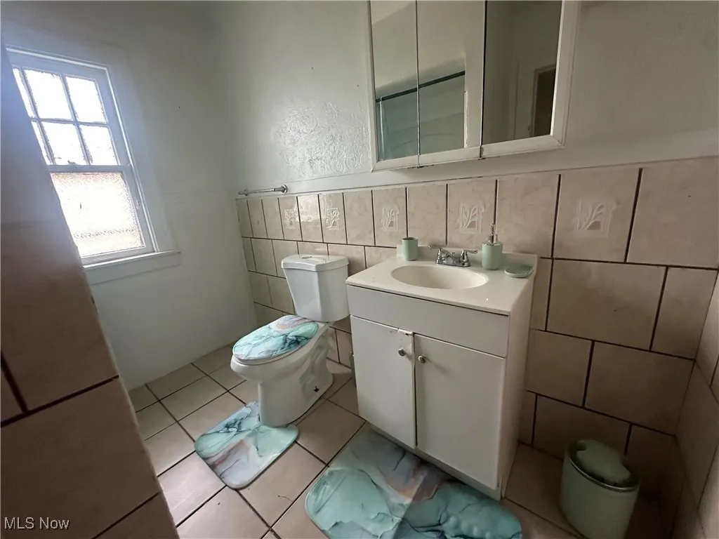 Bathroom featuring toilet, tile walls, and vanity