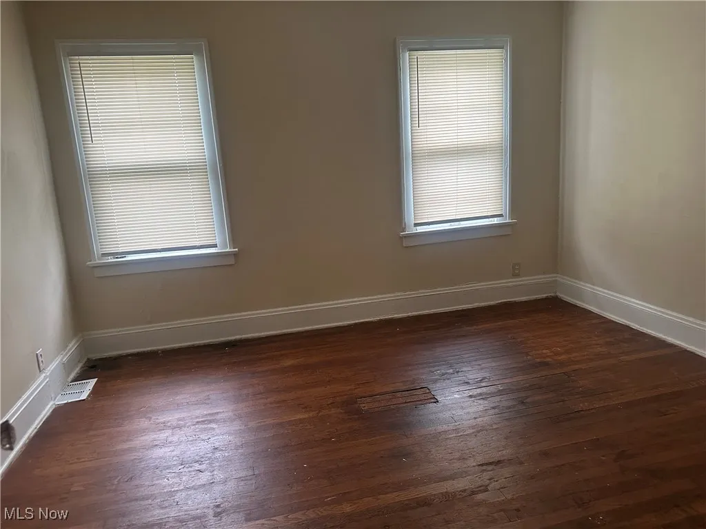 Unfurnished room with dark wood-type flooring, baseboards, and healthy amount of natural light
