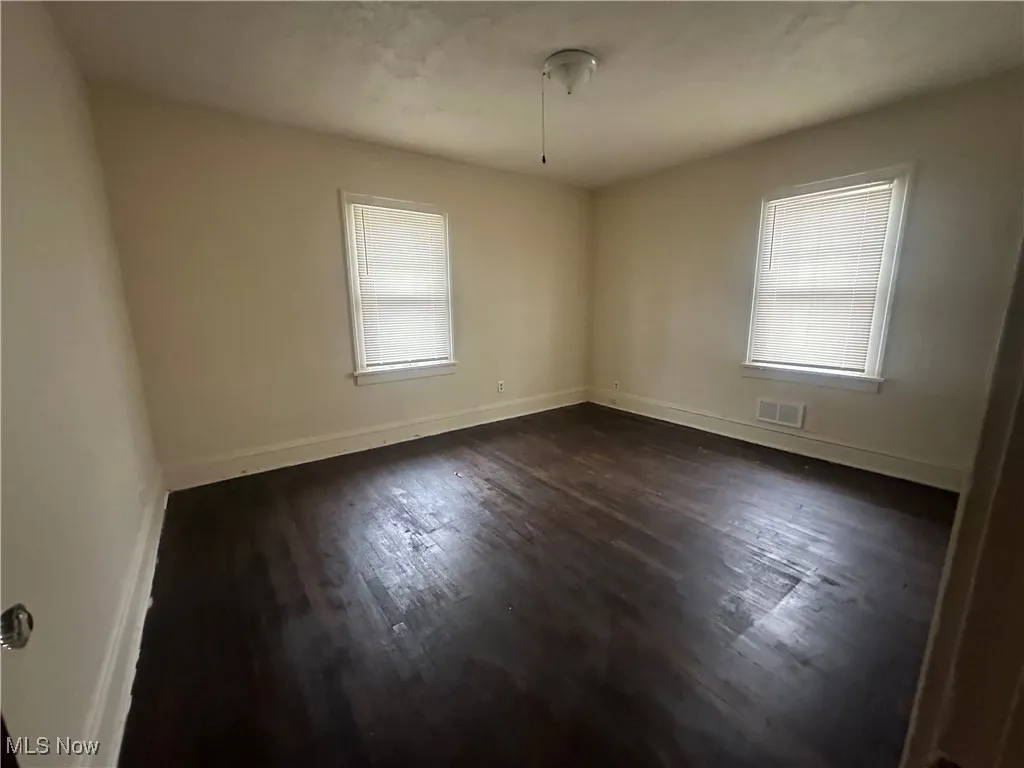 Spare room featuring dark wood-type flooring and baseboards