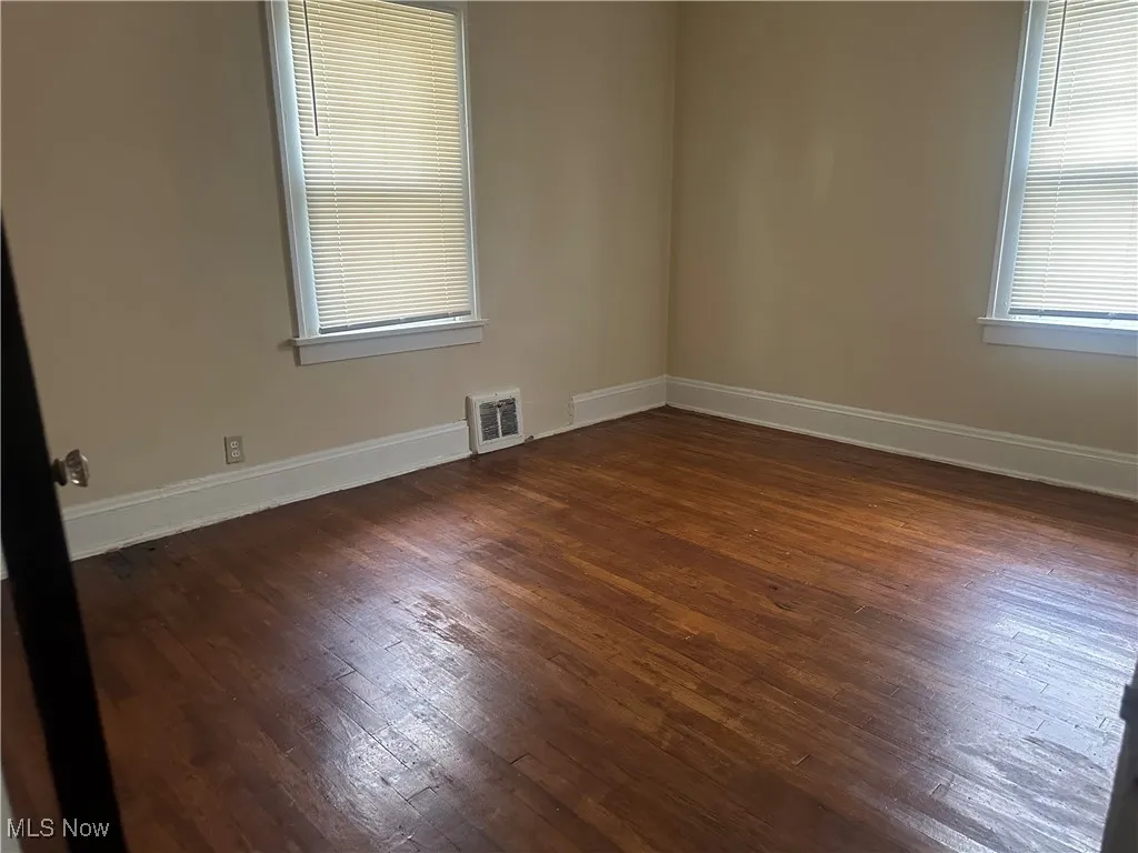 Empty room with dark wood finished floors and baseboards