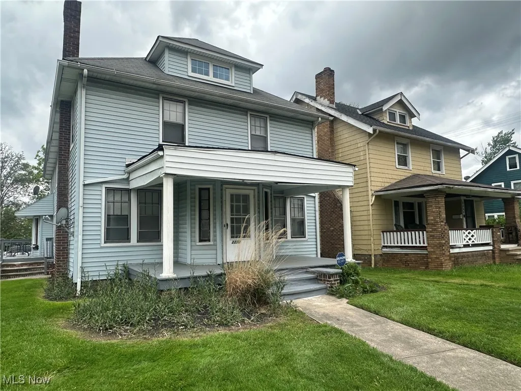 American foursquare style home with a porch, a chimney, and a front yard