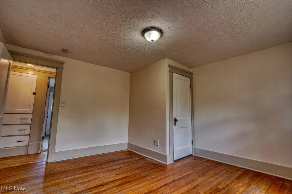 Unfurnished room featuring wood finished floors, a textured ceiling, and baseboards