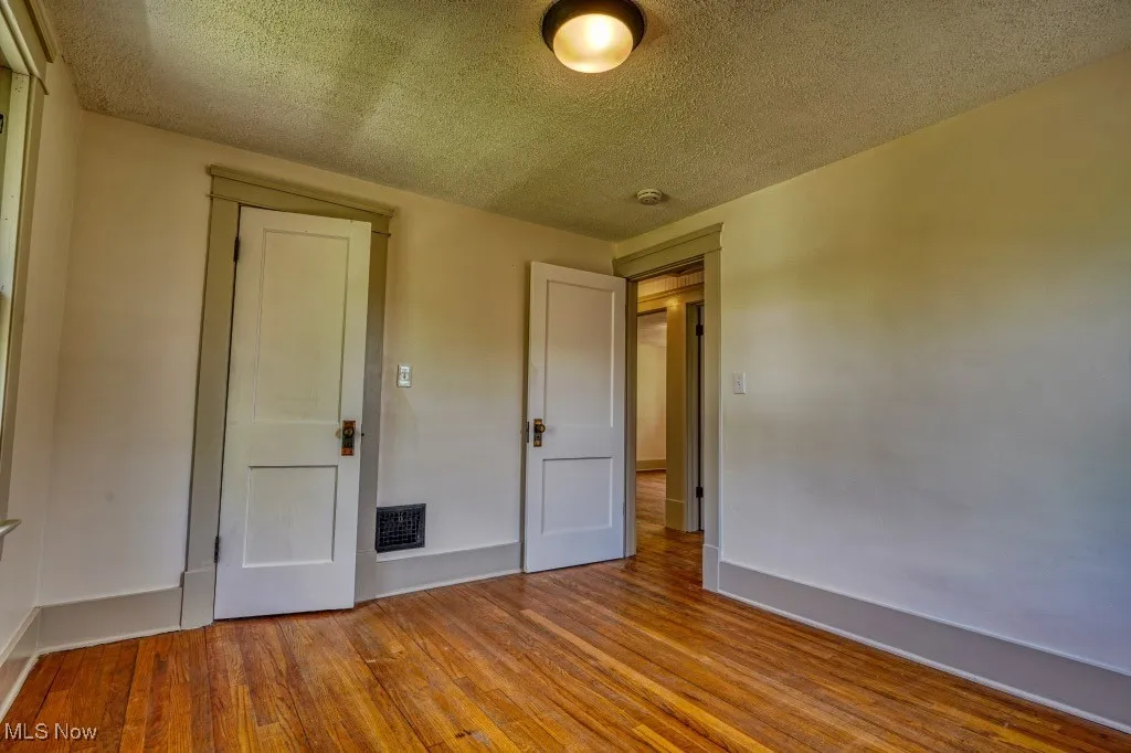 Unfurnished bedroom featuring wood finished floors, a textured ceiling, and baseboards