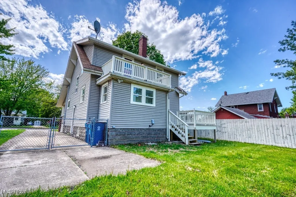 Back of house featuring a balcony, a gate, and a chimney