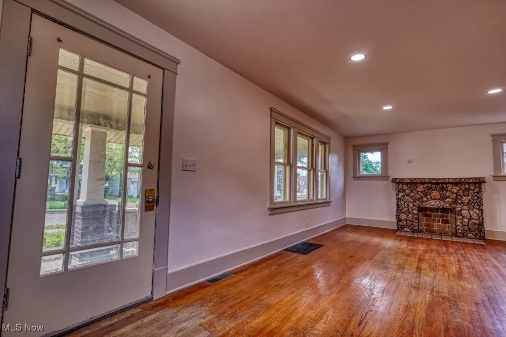 Unfurnished living room with wood finished floors, baseboards, recessed lighting, and a fireplace