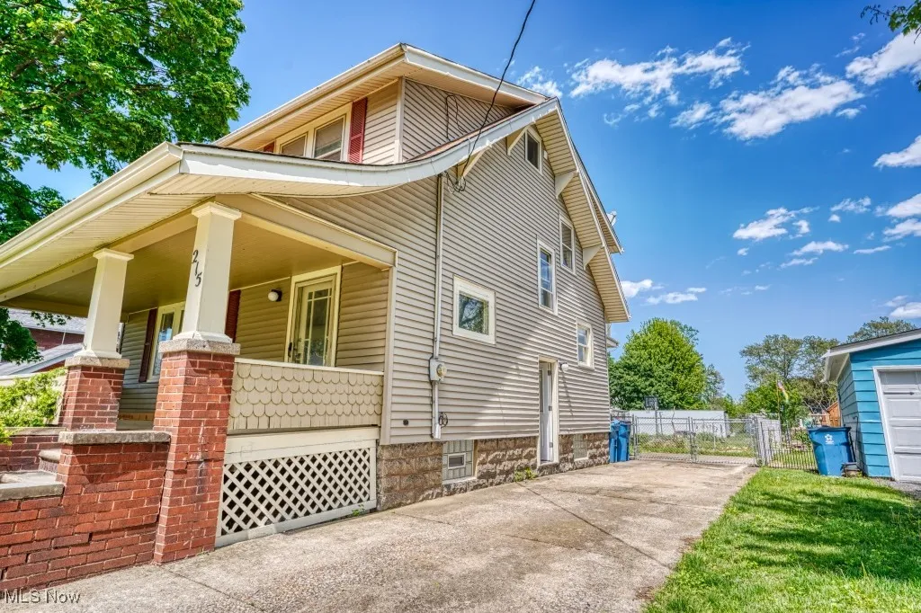View of side of property featuring a porch, concrete driveway, and fence