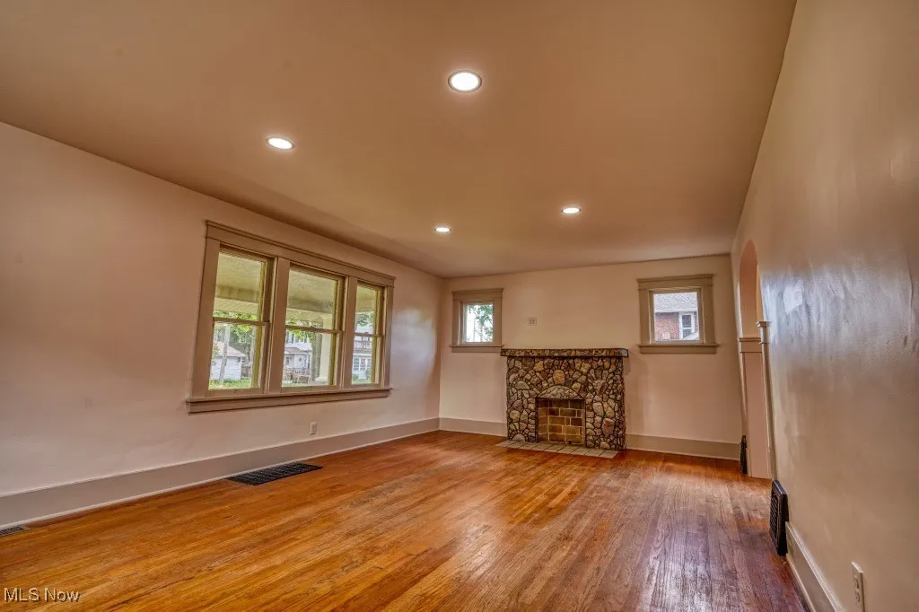 Unfurnished living room featuring hardwood / wood-style flooring, baseboards, recessed lighting, and a fireplace