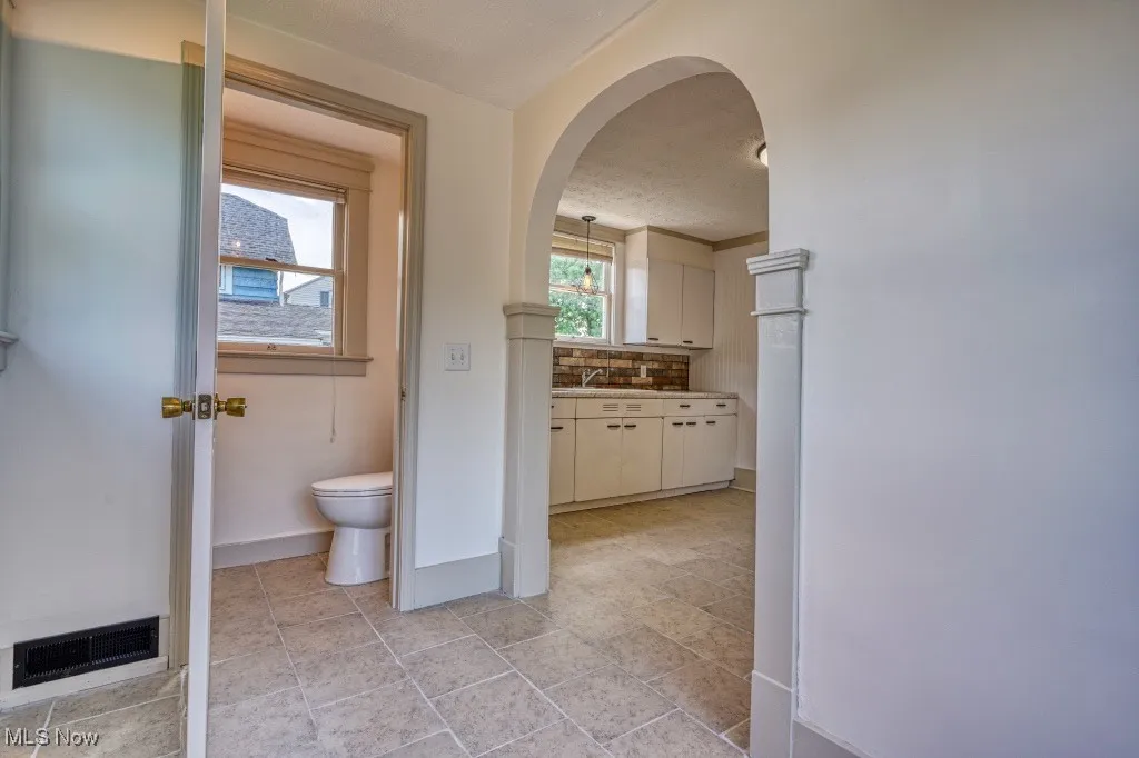 Bathroom with decorative backsplash, toilet, vanity, baseboards, and a textured ceiling
