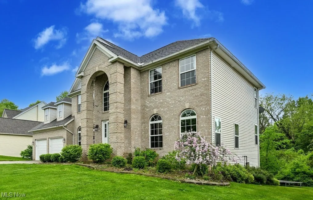 View of front of house featuring brick siding, a front lawn, and a garage