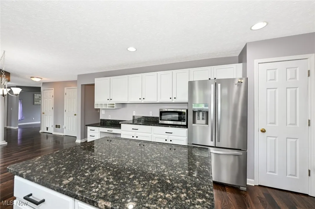 Kitchen with appliances with stainless steel finishes, dark wood-style floors, white cabinetry, a textured ceiling, and recessed lighting