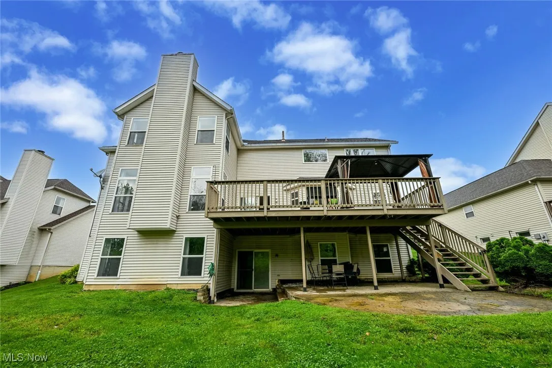 Rear view of house with a deck, a lawn, a chimney, and a patio area with walkout basement