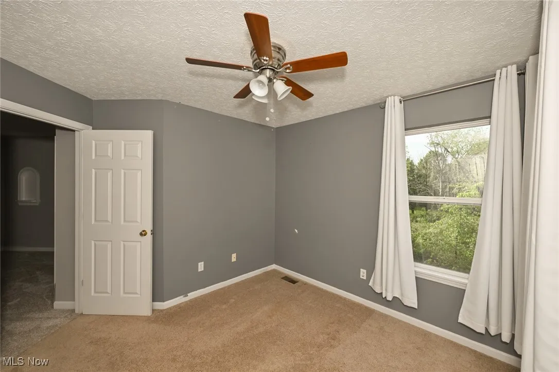 bdrm 4 Carpeted empty room with ceiling fan, baseboards, and a textured ceiling