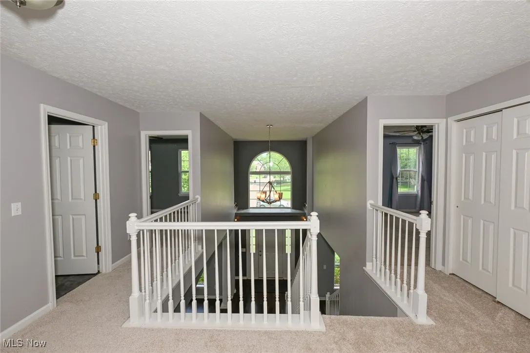 Corridor featuring an upstairs landing, carpet, plenty of natural light, and a textured ceiling