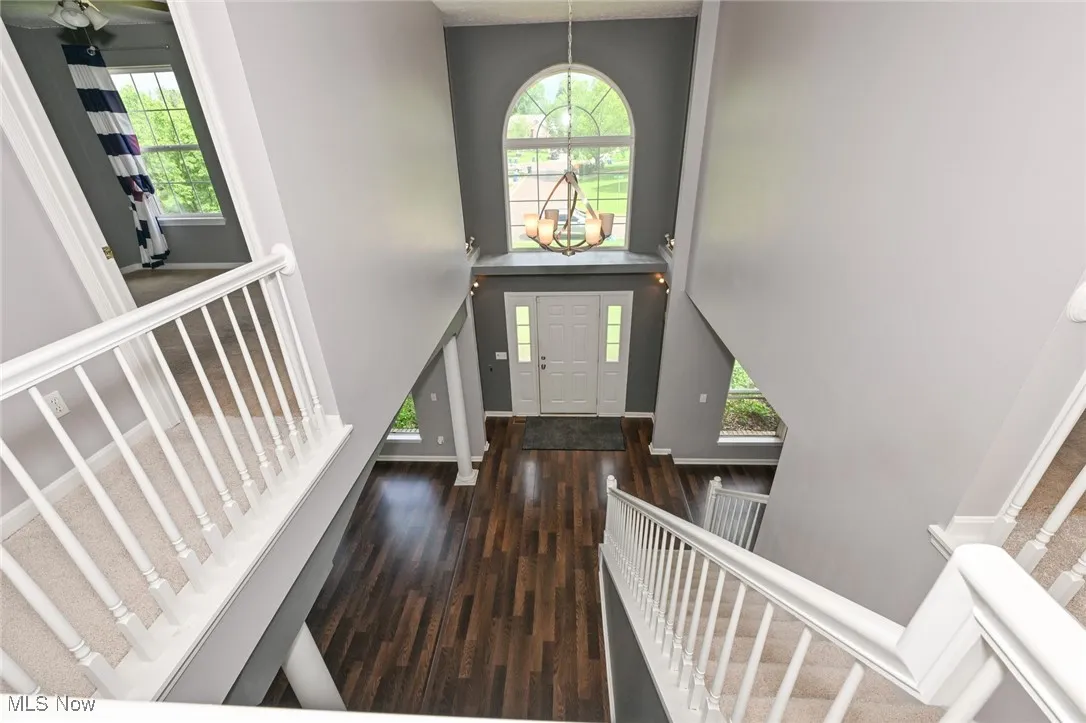 Entryway with stairs, wood finished floors, a towering ceiling, and baseboards