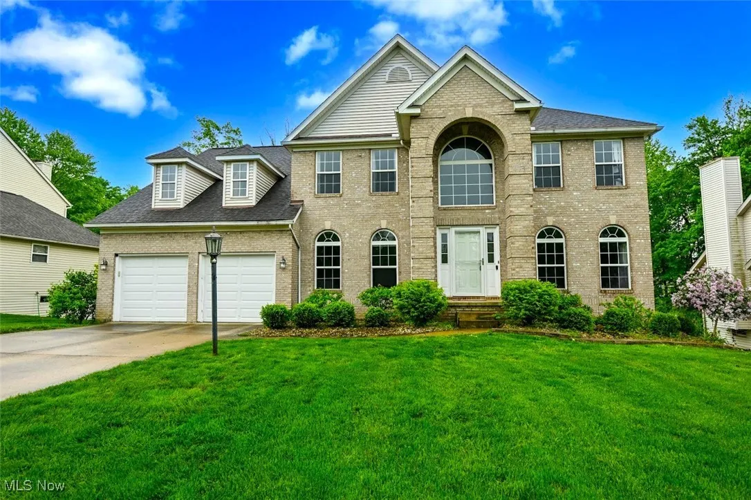 View of front of house with brick siding, an attached garage, a front yard, and concrete driveway