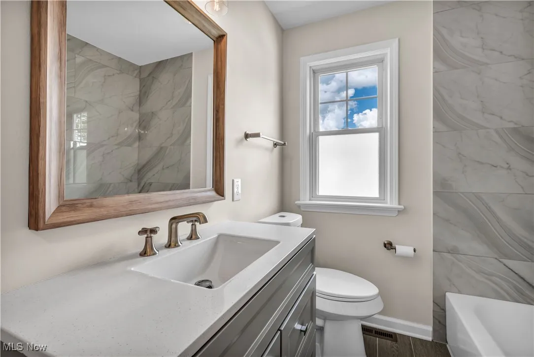 Bathroom featuring toilet, vanity, a bathtub, a shower, and baseboards