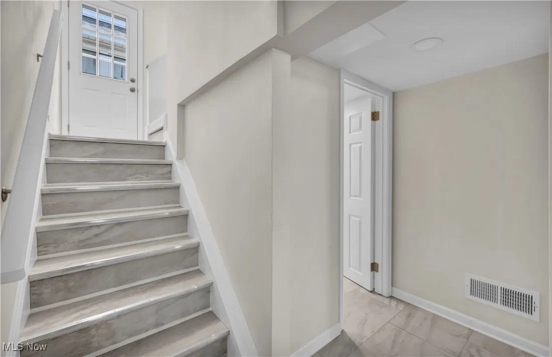 Staircase with marble look tile flooring and baseboards