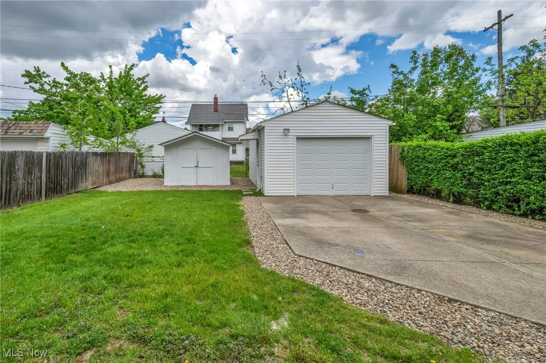 Detached garage with concrete driveway and a shed