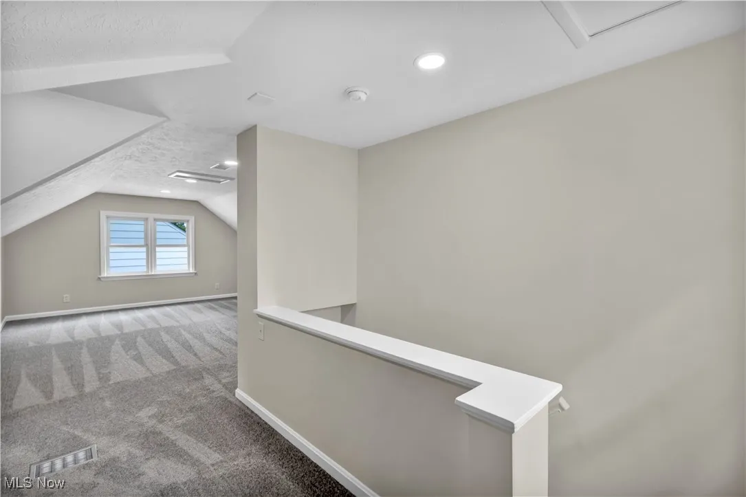 Hallway featuring vaulted ceiling, baseboards, a textured ceiling, carpet, and recessed lighting