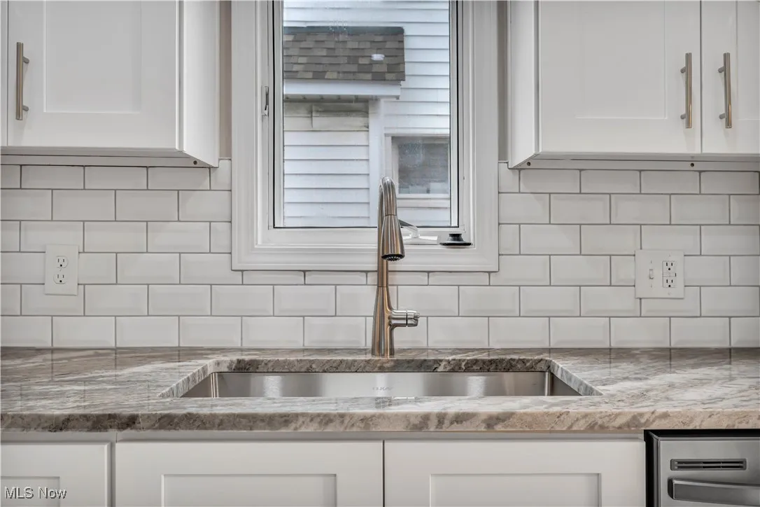 Kitchen featuring a sink, white cabinetry, and backsplash