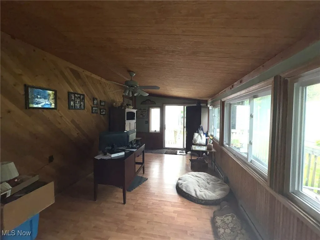 Sunroom / solarium featuring healthy amount of natural light, wood ceiling, lofted ceiling, wooden walls, and wood finished floors