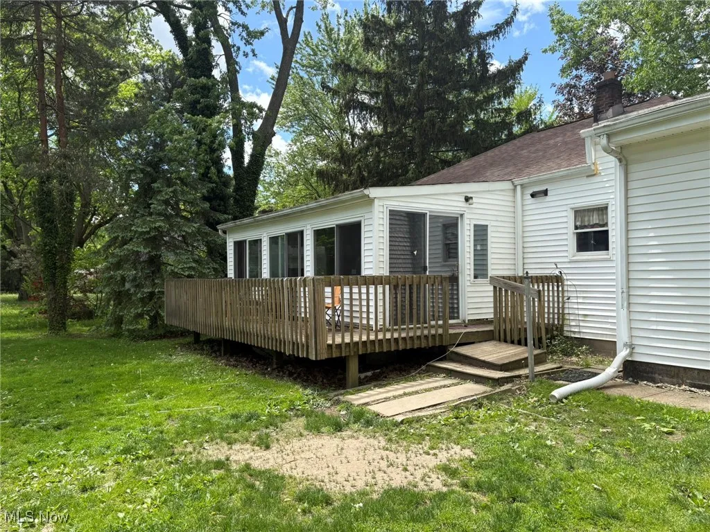 Back of house with a wooden deck, a yard, a chimney, and a shingled roof