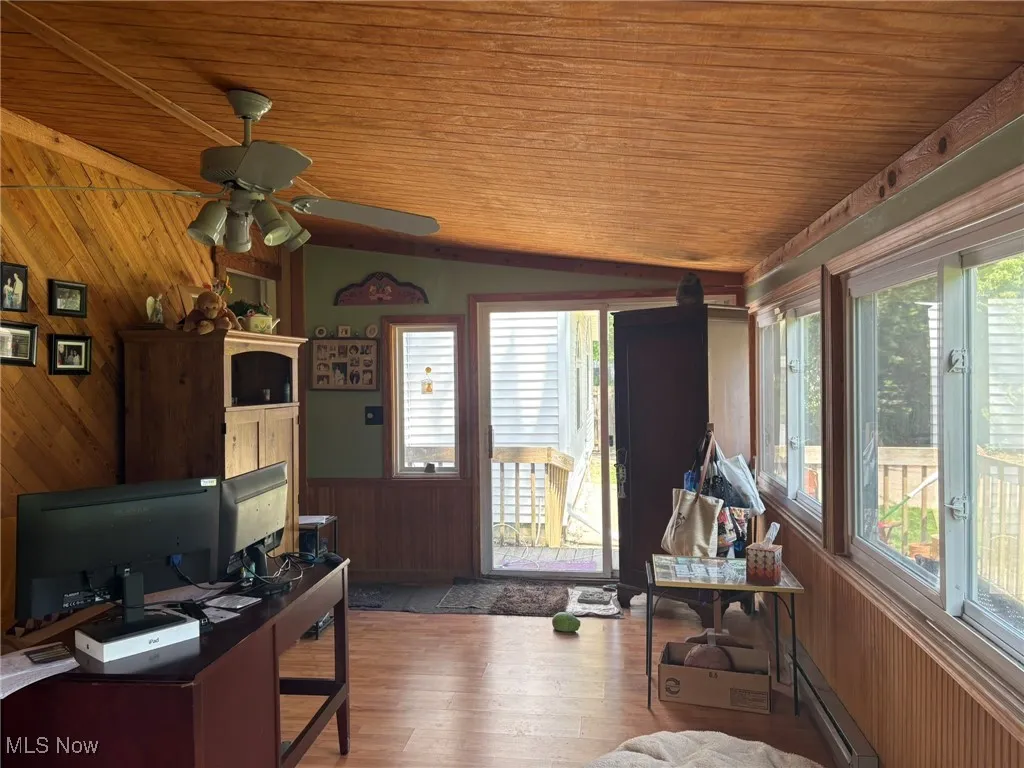 Office area with wood walls, wood ceiling, wood finished floors, a baseboard heating unit, and lofted ceiling