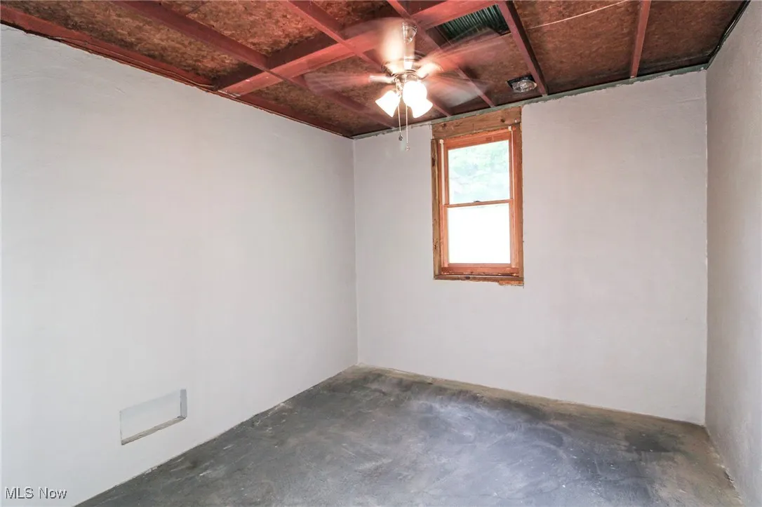 Unfurnished room featuring a ceiling fan and unfinished concrete floors