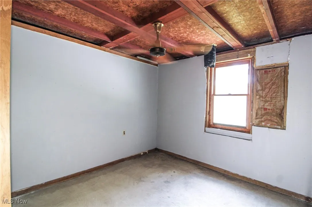 Empty room featuring unfinished concrete floors and baseboards