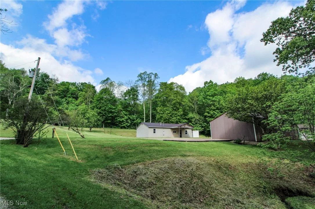 View of grassy yard featuring a wooded view and an outbuilding