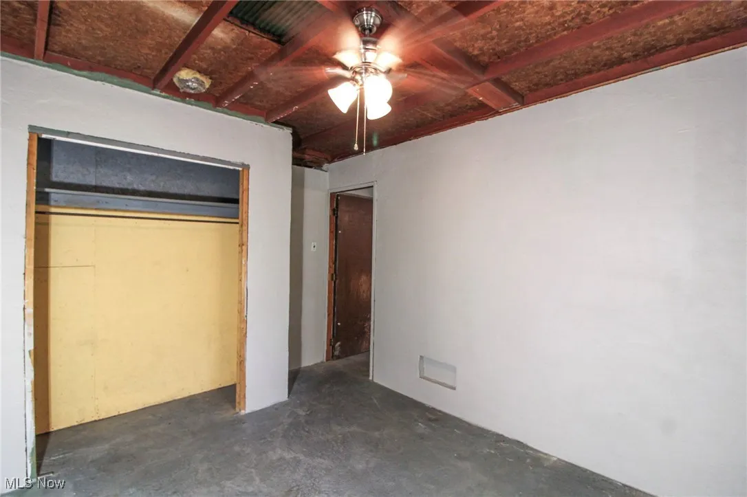 Unfurnished bedroom featuring concrete flooring and ceiling fan