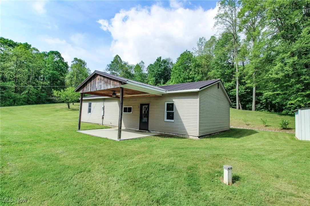 Rear view of house with a patio, ceiling fan, a yard, and metal roof