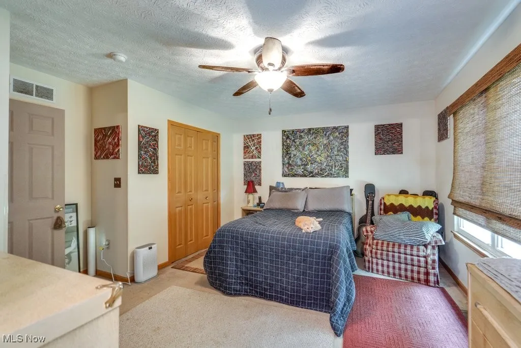 Carpeted bedroom featuring baseboards, ceiling fan, a closet, and a textured ceiling