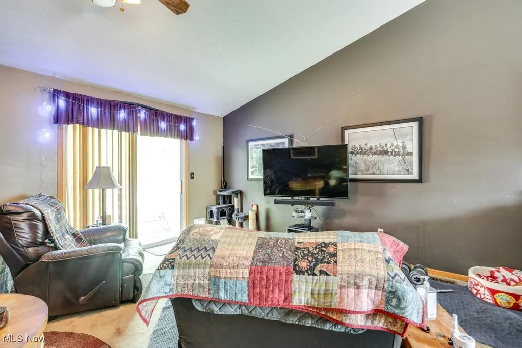 Carpeted living area featuring ceiling fan and lofted ceiling