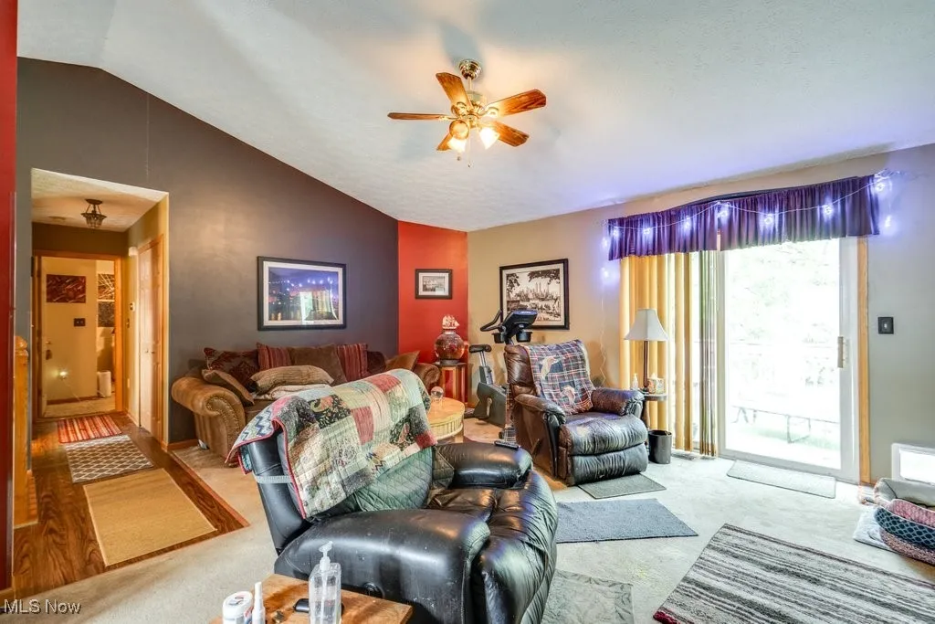 Carpeted living area with lofted ceiling and ceiling fan