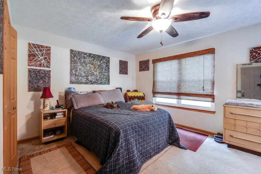 Bedroom featuring carpet floors, baseboards, a ceiling fan, and a textured ceiling