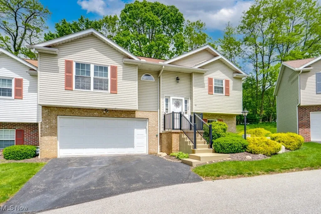 Raised ranch featuring a garage, asphalt driveway, and brick siding