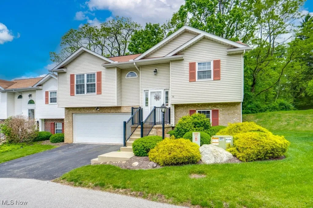 Split foyer home with brick siding, asphalt driveway, an attached garage, and a front yard